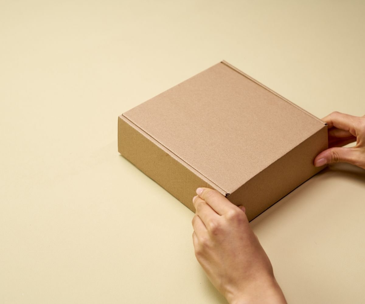 Hands opening a plain kraft product launch box
